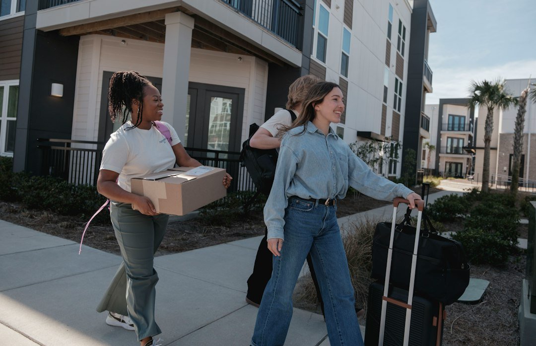 Illustrative people carrying moving boxes outside an apartment building for Broomfield apartment moving services